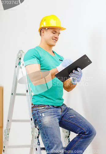 Image of smiling man in protective helmet with clipboard