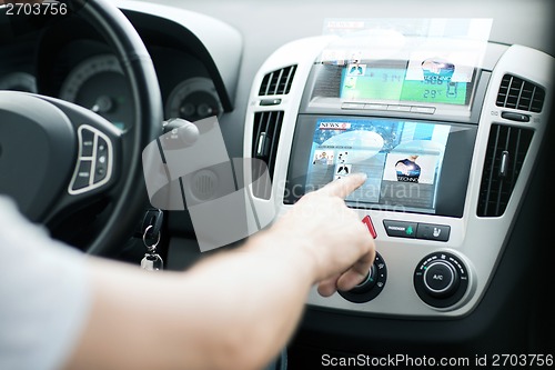 Image of man using car control panel to read news