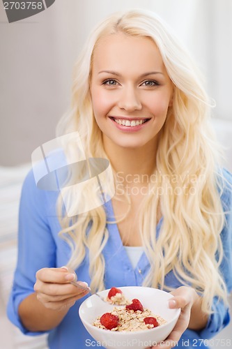 Image of smiling woman with bowl of muesli having breakfast