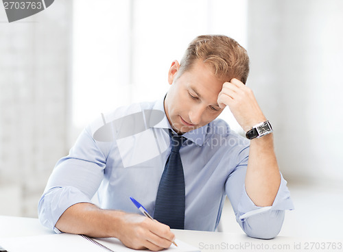 Image of businessman writing in notebook