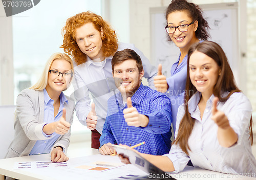 Image of creative team with papers showing thumbs up