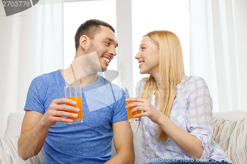 Image of smiling happy couple at home drinking juice