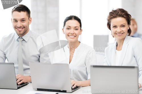 Image of group of people working with laptops in office