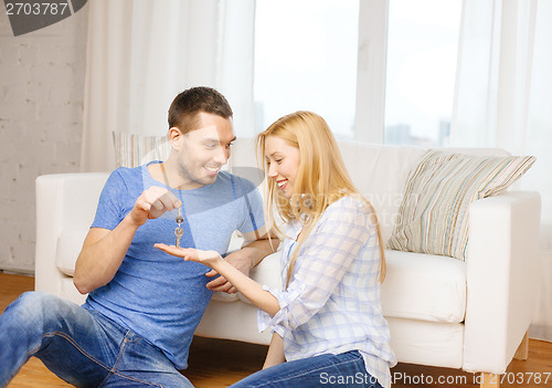 Image of man giving keys to girlfriend or wife at home