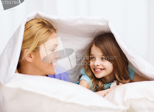 Image of mother and little girl under blanket at home