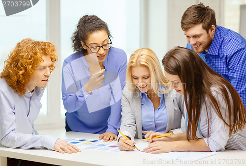 Image of smiling creative team looking over clothes designs