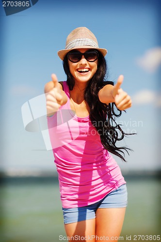 Image of girl showing thumbs up on the beach