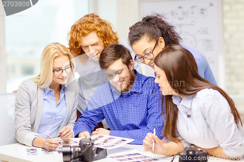 Image of smiling team with photocamera and images in office