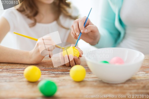 Image of close up of little girl and mother coloring eggs