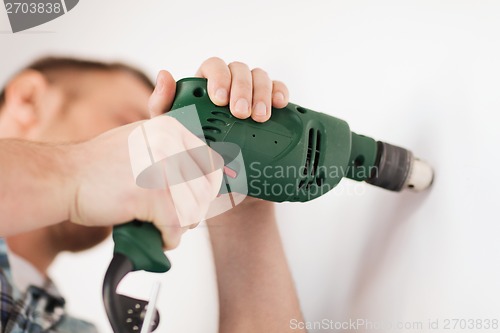 Image of man with electric drill making hole in wall