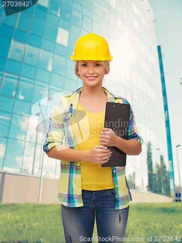 Image of smiling woman in helmet with clipboard