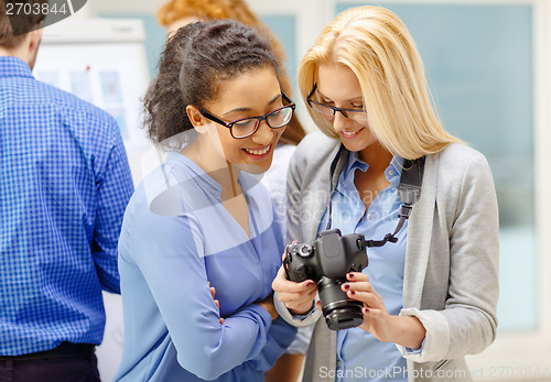 Image of two women looking at digital camera at office