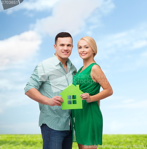 Image of smiling couple holding green paper house