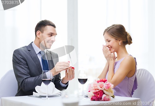 Image of man proposing to his girlfriend at restaurant