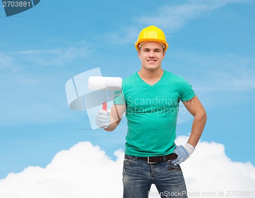 Image of smiling manual worker in helmet with paint roller