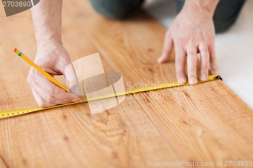 Image of close up of male hands measuring wood flooring