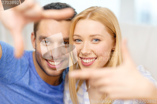 Image of smiling happy couple making frame gesture at home