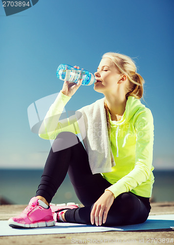 Image of woman drinking water after doing sports outdoors