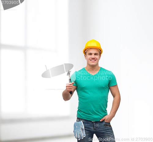 Image of smiling manual worker in helmet with hammer