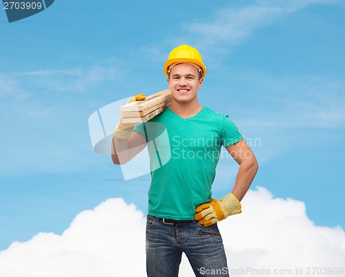 Image of smiling manual worker in helmet with wooden boards