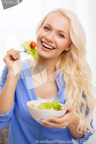 Image of smiling young woman with green salad at home