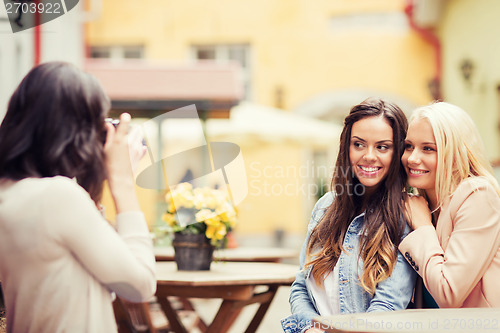 Image of beautiful girls taking picture in cafe in city