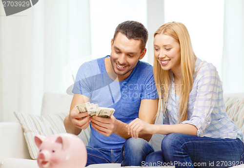 Image of smiling couple counting money at home