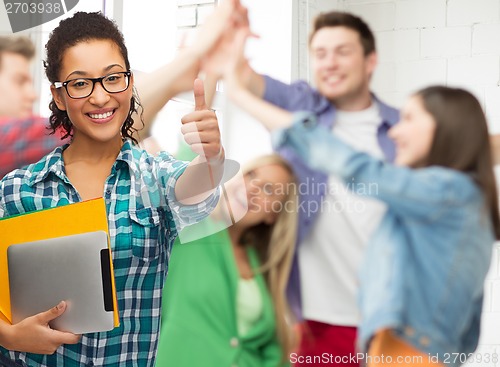 Image of student in eyeglasses with folders and tablet pc