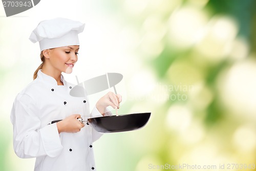 Image of smiling female chef with pan and spoon