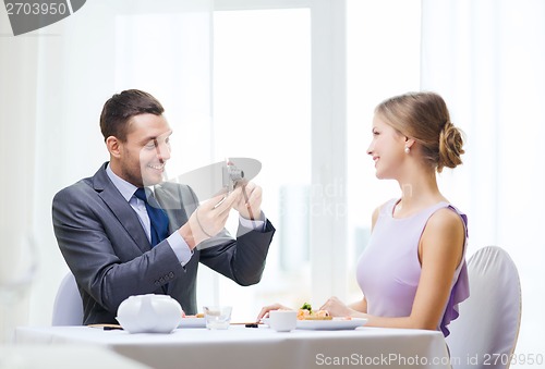 Image of smiling man taking picture with digital camera