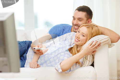 Image of smiling couple watching movie at home