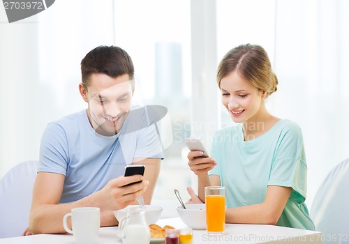 Image of smiling couple with smartphones reading news