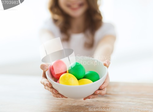 Image of close up of girl holding bowl with colored eggs