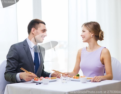 Image of smiling couple eating sushi at restaurant