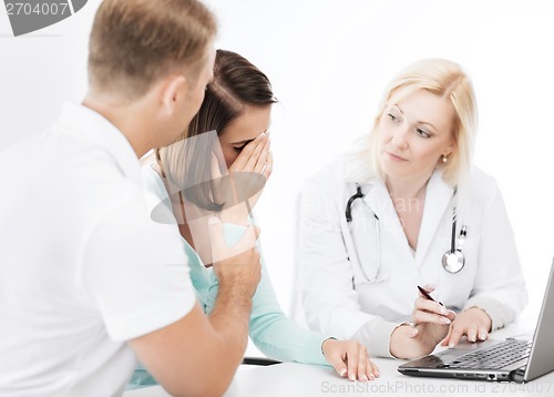 Image of doctor with patients looking at laptop