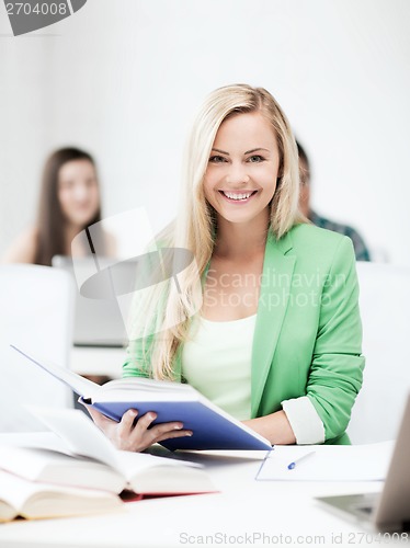 Image of smiling young woman reading book at school