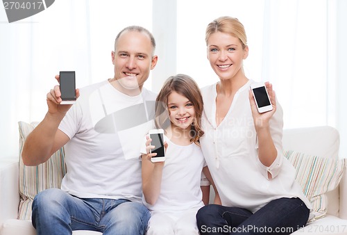 Image of parents and little girl with smartphones at home