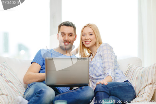 Image of smiling happy couple with laptop at home