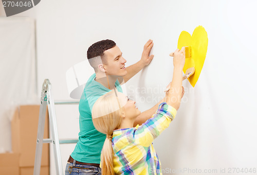 Image of smiling couple painting small heart on wall