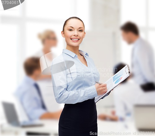 Image of young smiling businesswoman with clipboard and pen