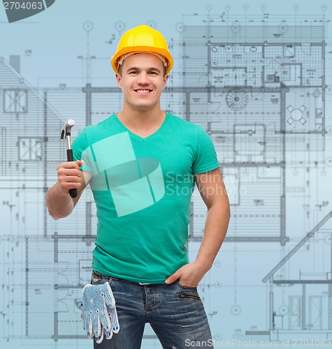 Image of smiling manual worker in helmet with hammer