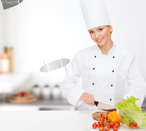 Image of smiling female chef chopping vagetables