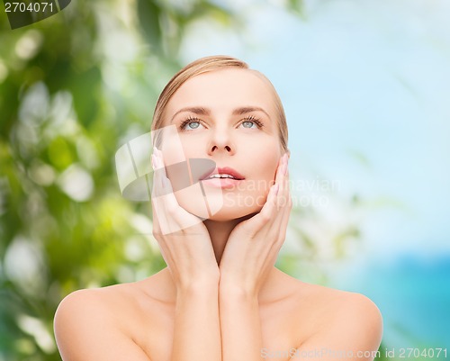 Image of beautiful woman touching her face and looking up