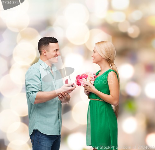 Image of smiling couple with flower bouquet and ring