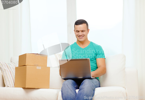 Image of man with laptop and cardboard boxes at home