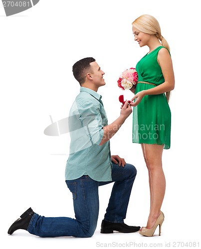 Image of smiling couple with flower bouquet and ring