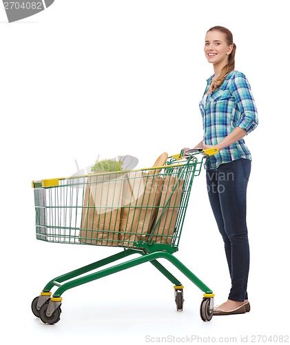 Image of smiling young woman with shopping cart and food