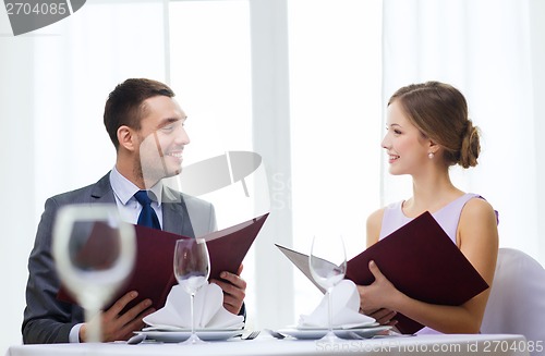 Image of smiling couple with menus at restaurant