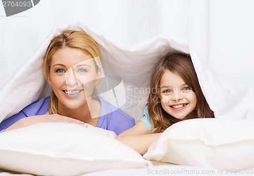 Image of mother and little girl under blanket at home