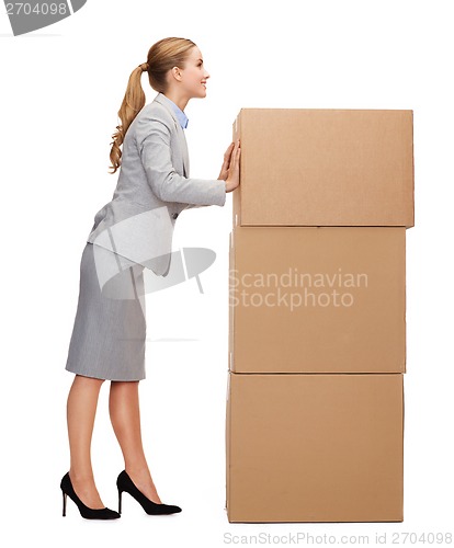 Image of smiling businesswoman pushing tower of cardboards